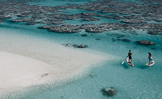 Personas realizando deporte en Polinesia Francesa agua cristalina