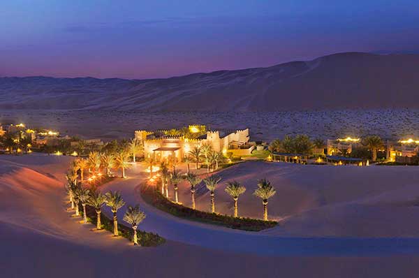 Hotel desierto Qasar Al Sarab iluminado a lo lejos por la noche