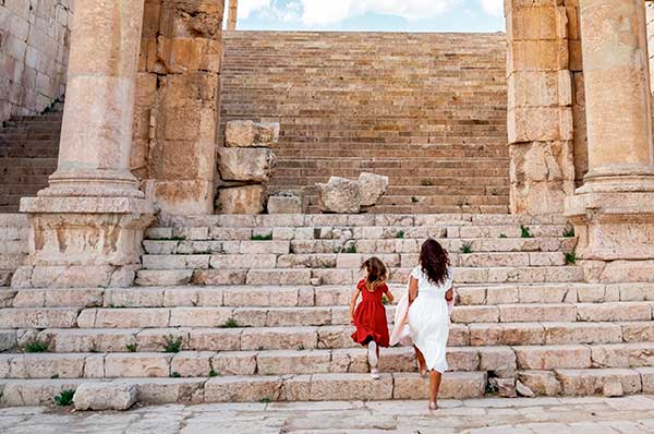 Una familia jugando en ruinas romanas en Jordania fondo pilares