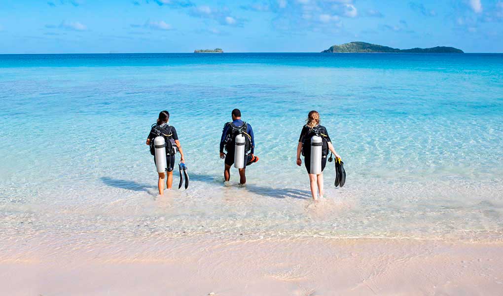 Tres persona entrando al mar Fiji para buceo Kokomo Private Island